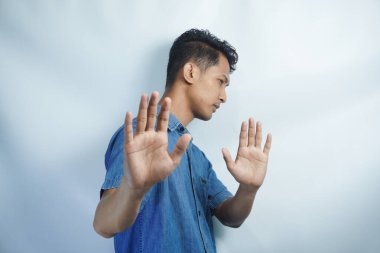 İzole edilmiş beyaz arka plandaki çekici Asyalı genç adam korkmuş ve korkmuş ifadeyle dehşete düşmüş. Ellerinle hareket etmeyi kes, şok içinde çığlık atmayı kes. Panik konsepti.