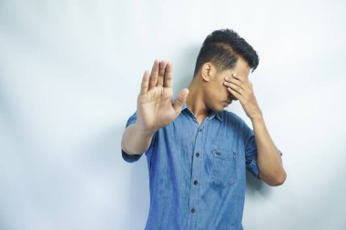 İzole edilmiş beyaz arka plandaki çekici Asyalı genç adam korkmuş ve korkmuş ifadeyle dehşete düşmüş. Ellerinle hareket etmeyi kes, şok içinde çığlık atmayı kes. Panik konsepti.