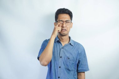 Beyaz arka planda gözlük takan genç Asyalı bir adam. Ağlarken suratını ellerle kapatan üzgün bir ifade. depresyon kavramı.