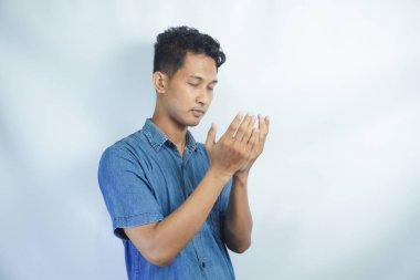 Stüdyoda beyaz bir arka planda Tanrı 'dan mucize ya da yardım isteyen bir adamla dua, inanç ve maket. Güven, din ve ruhani inanç için dua eden genç ve yakışıklı bir erkek.