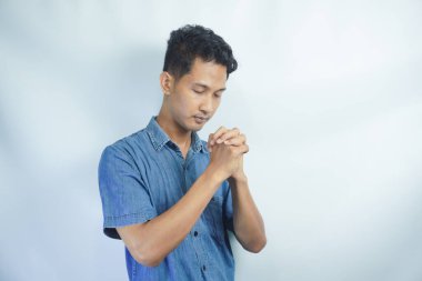 Stüdyoda beyaz bir arka planda Tanrı 'dan mucize ya da yardım isteyen bir adamla dua, inanç ve maket. Güven, din ve ruhani inanç için dua eden genç ve yakışıklı bir erkek.