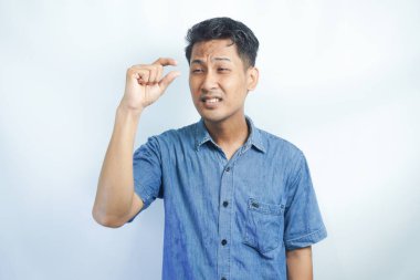 Genç Asyalı adam görünmeyen küçük nesne ya da nesne gösteriyor. Küçük konsept.