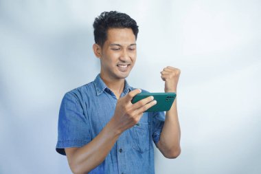 Asyalı bir adamın akıllı telefonu tutarken görüntüsü. Endonezyalı adamın ifadesi cep telefonunu görünce şok oldu.