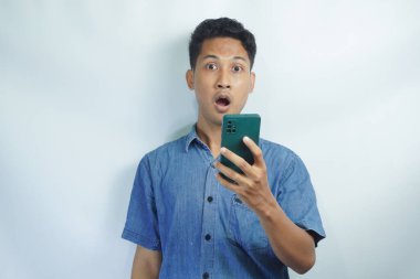 Asyalı bir adamın akıllı telefonu tutarken görüntüsü. Endonezyalı adamın ifadesi cep telefonunu görünce şok oldu.