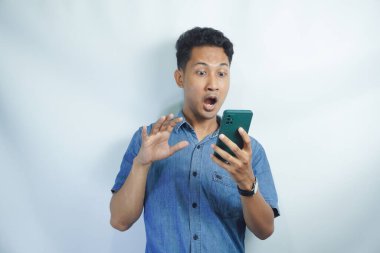 Asyalı bir adamın akıllı telefonu tutarken görüntüsü. Endonezyalı adamın ifadesi cep telefonunu görünce şok oldu.