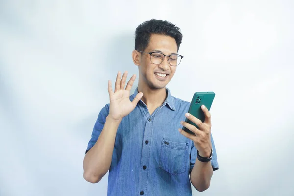 Hello. Happy millennial man wave hand hi look at smartphone screen start talk by video call with friend dating in videochat. Smiling young male begin phone conversation in conference app record vlog
