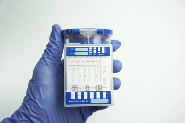 交上蓝色手套 里面装着一个空的容器供分析 药物测试的概念 因白人背景而被隔离 — 图库照片