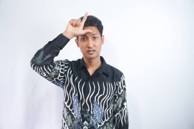 Beyaz arka planda batik tişört giyen yakışıklı bir genç. Alnında parmakları olan insanlarla alay ediyor. Ezik hareketler yapıyor, alay ediyor ve hakaret ediyor..