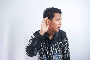 Işık stüdyosunda Batik dinleme cihazı takan Asyalı bir adam.