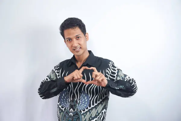 Νεαρός Άνδρας Φορώντας Πουκάμισο Μπατίκ Κάνει Χειρονομία Καρδιάς Στο Στήθος — Φωτογραφία Αρχείου