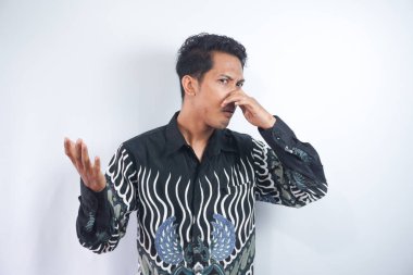 Sıkılmış ya da kafası karışmış Batik tişörtlü genç bir adamın portresi burnunu çimdikliyor ve el hareketini durdurma işareti gösteriyor. Beyaz arka planda izole edilmiş kapalı stüdyo görüntüleri..