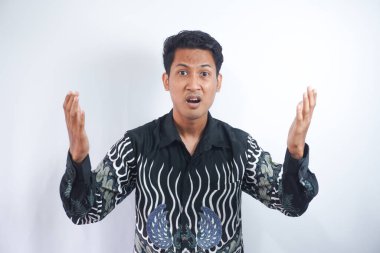 Yardım isteyen adam ne yapacağını bilmiyor. Şaşkın, şaşkın ve kararsız, batik tişörtlü, sakar, sakar, el kaldıran, omuz silken, yardım edemeyen, cevap veremeyen, özür dileyen, sırıtan,