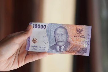 Bir kadının eli 2023 'te basılmış bir rupiah banknotunu tutuyor..