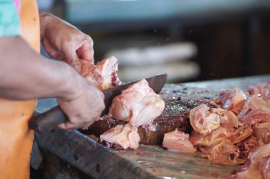 Bir tavuk satıcısı geleneksel bir markette alıcılar için tavuk eti kesiyor.