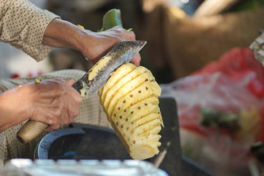 Taze ananas derisi soyan kadın elleri.