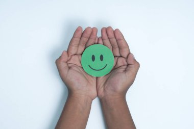 Ellerinde yeşil gülen surat, iyi geri bildirim notu, olumlu müşteri değerlendirmesi, deneyim, tatmin anketi, gülümseyen akıl sağlığı, çocuk sağlığı, beyaz arka planda dünya ruh sağlığı günü