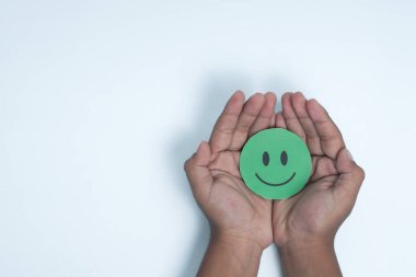 Ellerinde yeşil gülen surat, iyi geri bildirim notu, olumlu müşteri değerlendirmesi, deneyim, tatmin anketi, gülümseyen akıl sağlığı, çocuk sağlığı, beyaz arka planda dünya ruh sağlığı günü