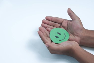 Ellerinde yeşil gülen surat, iyi geri bildirim notu, olumlu müşteri değerlendirmesi, deneyim, tatmin anketi, gülümseyen akıl sağlığı, çocuk sağlığı, beyaz arka planda dünya ruh sağlığı günü