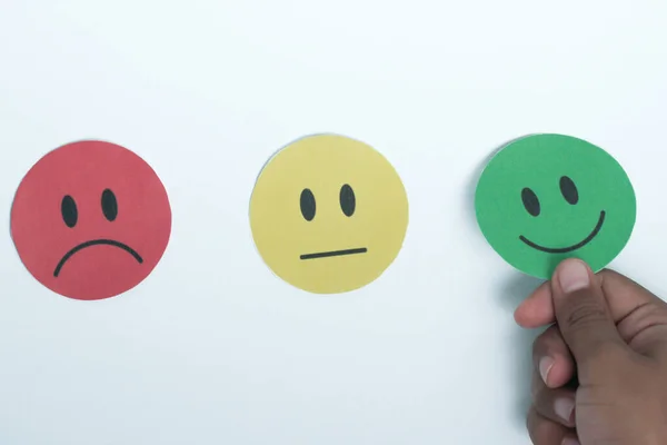 Elle seçilen yeşil gülücük kağıt kesiği, geri bildirim notu ve olumlu müşteri değerlendirmesi, memnuniyet anketi, zihinsel sağlık değerlendirmesi, iyi hissetmek, dünya akıl sağlığı günü konsepti