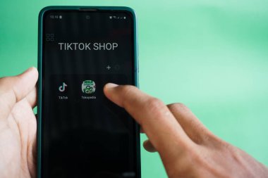 Jakarta, Endonezya - 12 Aralık 2023: İnsan eli ekranda Tiktok ve Tokopedia logoları olan bir android telefonu tutuyor. Etkili Odaklanma. Yumuşak Odaklanma