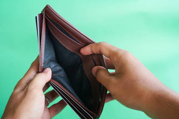 Man hand open an empty wallet on green background