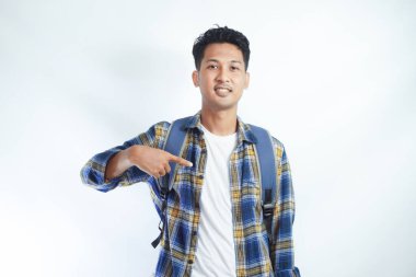 Heyecanlı genç Asyalı 20 'li yaşlarda sırt çantalı bir öğrenci beyaz arka planda kendini işaret ediyor. Lise üniversite konsepti