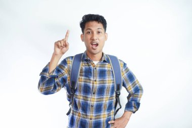 Üniversiteden heyecanlı genç Asyalı erkek öğrenci sırt çantalı, parmakla göstererek beyaz arka planda izole edilmiş bir fikri düşünüyor. Lise üniversite konsepti eğitimi
