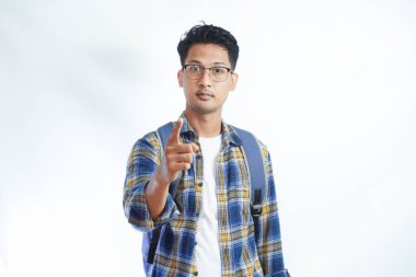 Sırt çantası gözlüklü kızgın Asyalı genç bir öğrenci beyaz arka planda izole edilmiş kamerayı işaret ediyor. Lise üniversite konsepti