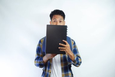 Sırt çantalı genç Asyalı öğrenciler beyaz arka planda izole edilmiş kitaplarla yüzlerinin yarısını kapattılar. Lise üniversite konsepti eğitimi