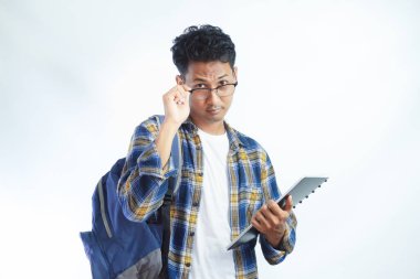 Sırt çantasında kitap tutan, kameraya bakan, beyaz arka planda izole edilmiş gözlükleri çıkaran dalgın Asyalı genç bir öğrenci. Lise üniversite konsepti eğitimi