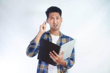 Sırt çantalı genç Asyalı öğrenciler ellerinde defterlerle beyaz arka planda izole edilmiş bir şeyi düşünüyorlar. Lise üniversite konsepti eğitimi