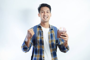 Sırtında para dolu cüzdan ve günlük kıyafetlerle gülümseyen Asyalı genç bir öğrenci beyaz arka planda izole edilmiş bir şekilde kutluyor.