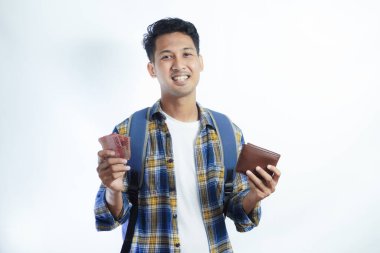 Sırt çantasında beyaz arka planda izole edilmiş para dolu cüzdan taşıyan sıradan giyinmiş gülümseyen Asyalı genç bir öğrenci. Lise Üniversite Konsepti Eğitimi