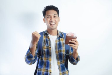 Sırtında para dolu cüzdan ve günlük kıyafetlerle gülümseyen Asyalı genç bir öğrenci beyaz arka planda izole edilmiş bir şekilde kutluyor.