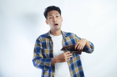 Yetişkin bir Asyalı, cüzdanını açarken üzgün bir ifadeyle kameraya bakıyor.