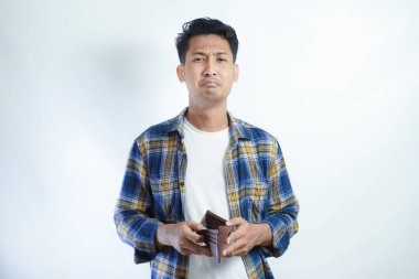 Yetişkin bir Asyalı, cüzdanını açarken üzgün bir ifadeyle kameraya bakıyor.