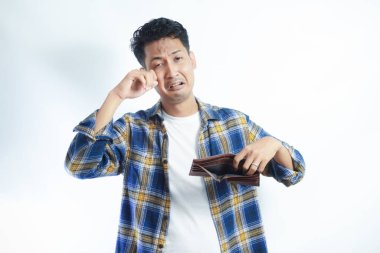 Yetişkin bir Asyalı, cüzdanını açarken üzgün bir ifadeyle kameraya bakıyor.