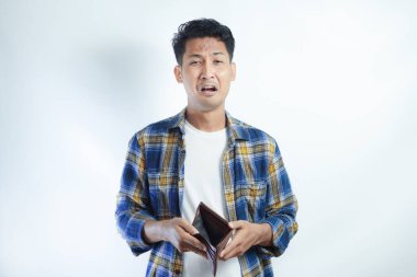 Yetişkin bir Asyalı, cüzdanını açarken üzgün bir ifadeyle kameraya bakıyor.