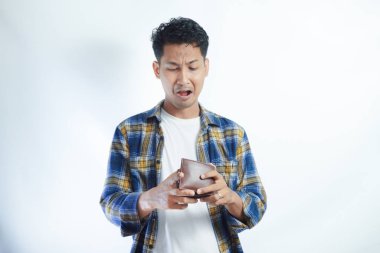 Yetişkin bir Asyalı, cüzdanını açarken üzgün bir ifadeyle kameraya bakıyor.