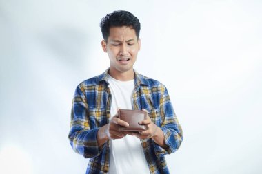 Yetişkin bir Asyalı, cüzdanını açarken üzgün bir ifadeyle kameraya bakıyor.