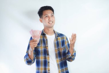 Yukarıdan bir şeye bakan bir adam elinde para tutarken mutlu bir ifadeyle düşer.