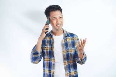 Yetişkin Asyalı bir adam cep telefonuna cevap verirken mutlu bir şekilde gülüyor.