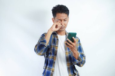 Sırt çantalı üzgün bir öğrenci telefonda kötü haber okur, telefonu olan bir adam akıllı telefonda internet sayfası, uygulamalar, aramalar, lise üniversite konsepti.