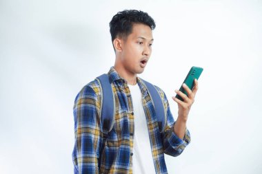 Sırt çantası gözlüklü, cep telefonu kullanan, internette sohbet eden ve beyaz arka planda izole edilmiş haberleri okuyan Asyalı bir öğrenci. Lise üniversite konsepti