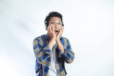 Beyaz arka planda izole edilmiş kameraya bakarken sırt çantası gözlüklü, heyecanlı ve şaşırmış Asyalı bir genç. Lise üniversite konsepti eğitimi