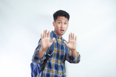 Sırt çantalı Korkak Asyalı genç bir öğrenci dur hareketi yapıyor ve kendini beyaz arka planda izole edilmiş bir şeyden korumaya çalışıyor. Lise üniversite konsepti