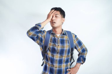 Kafası karışmış Asyalı bir öğrenci, günlük kıyafetler giyip, sırt çantasıyla yüzünü örterek beyaz arka planda tek başına dolaşmış. Lise üniversite konsepti