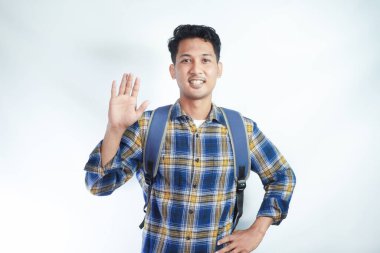 Sırt çantasıyla kolejden gülümseyen Asyalı genç bir erkek öğrenci beyaz arka planda el ele izole edilmiş bir arkadaşı selamlıyor. Lise üniversite konsepti eğitimi