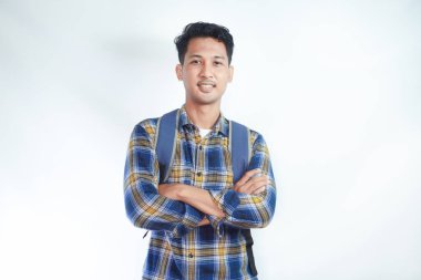 Sırt çantası katlanmış günlük kıyafetler giyen ve beyaz arka planda izole edilmiş kameraya bakan kendine güvenen Asyalı genç bir öğrenci. Lise üniversite konsepti