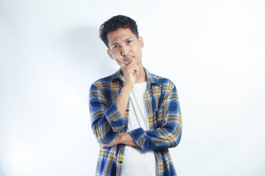 Sarı flanel tişört giyen yetişkin bir Asyalı düşünme hareketi gösteriyor.